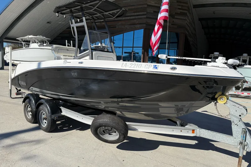 Slide: The Image of 2019 Yamaha Boats 210 FSH Sport on trailer, displayed outdoors with American flag. - 2