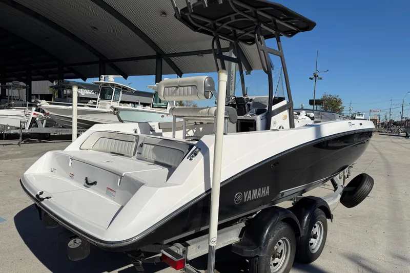Slide: The Image of 2019 Yamaha Boats 210 FSH Sport on trailer, parked outdoors under a canopy. - 7