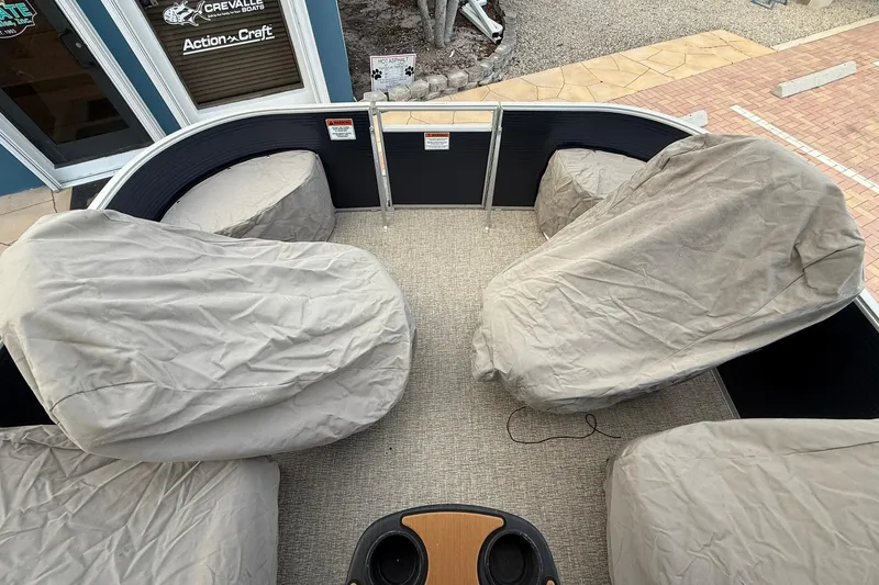 Slide: The Image of 2019 Bennington R 25 RL boat interior with covered seats, outdoor setting. - 28