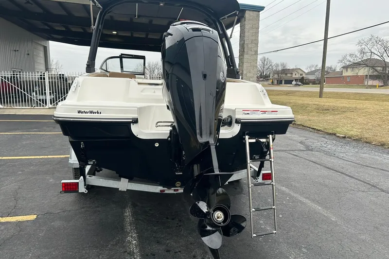 Slide: The Image of 2026 Bayliner VR4 Bowrider OB with outboard motor and ladder, parked outdoors. - 3
