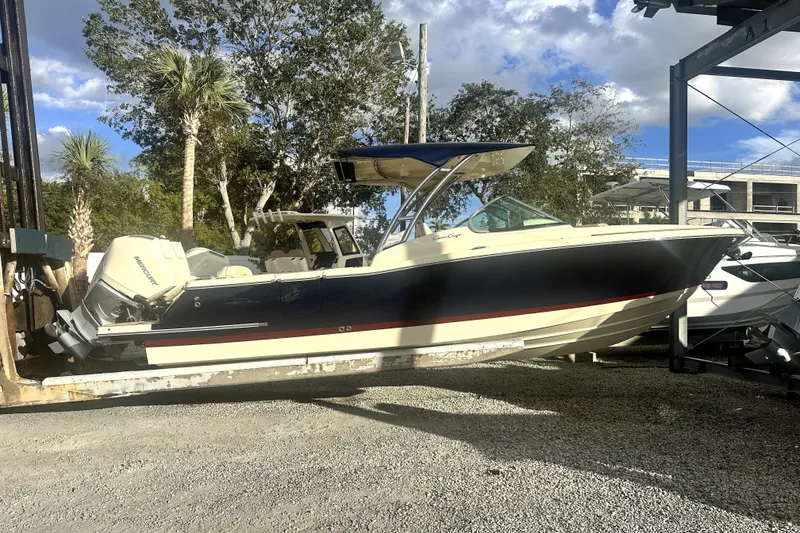 The Image of 2026 Chris-Craft Calypso 28 boat on a trailer, parked outdoors under a blue sky. - 0