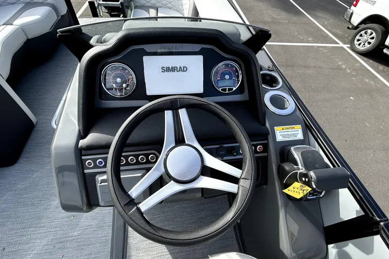 Slide: The Image of 2026 Godfrey Monaco 235 ULC boat dashboard with steering wheel and Simrad display. - 4