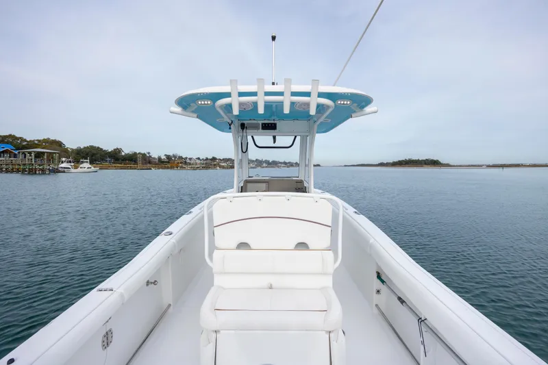 Slide: The Image of 2018 Sea Hunt Ultra 255 SE boat on calm water, showcasing spacious deck and seating. - 10