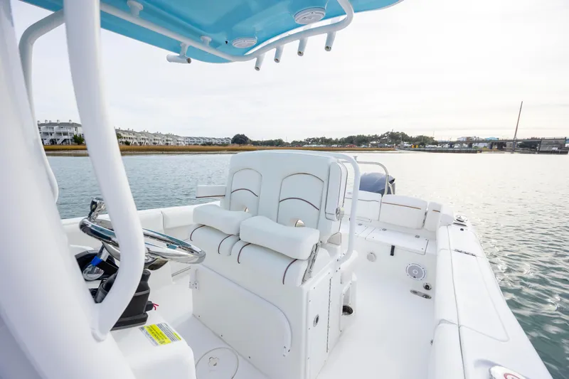 Slide: The Image of 2018 Sea Hunt Ultra 255 SE boat interior with helm and seating, on calm water. - 15