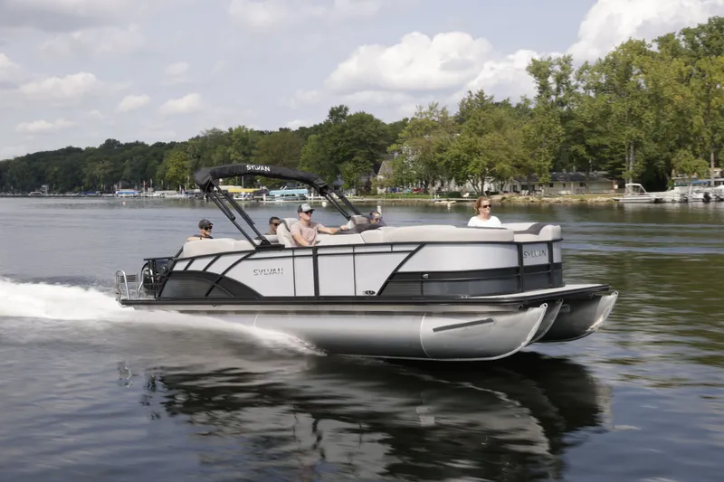 The Image of 2026 Sylvan L-3 ULZ pontoon boat cruising on a serene lake. - 0
