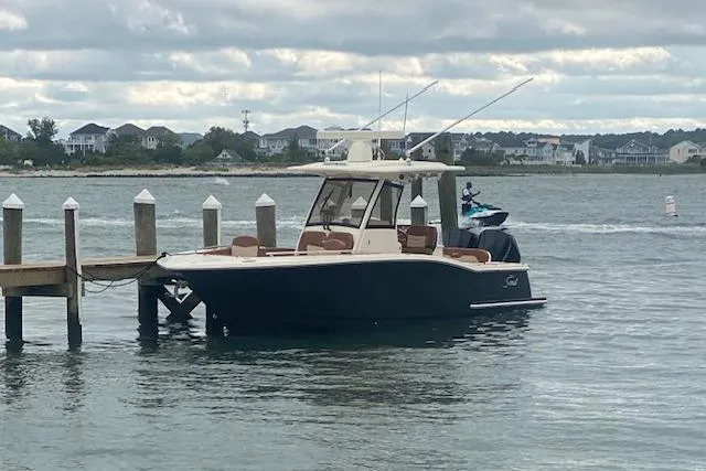 Slide: The Image of 2023 Scout 277 LXF boat on calm water near rocky shoreline. - 4