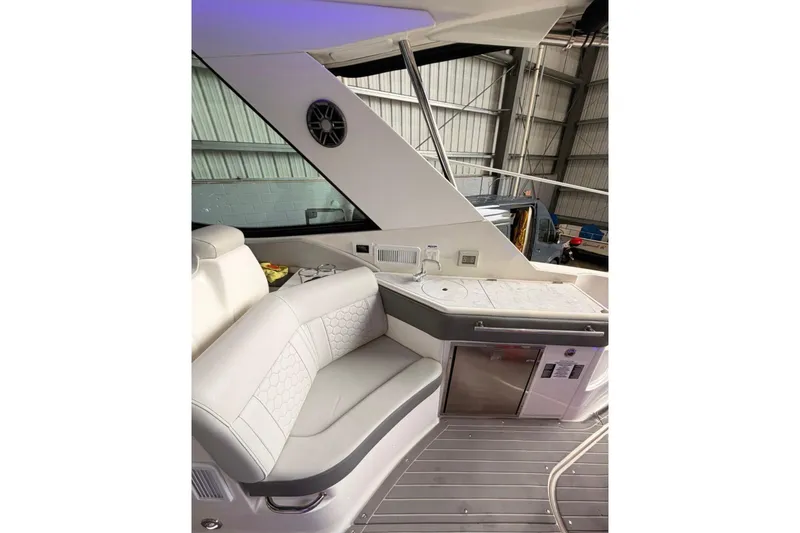 Slide: The Image of 2022 Sea Ray Sundancer 320 Outboard interior with seating and kitchenette in a boat garage. - 5