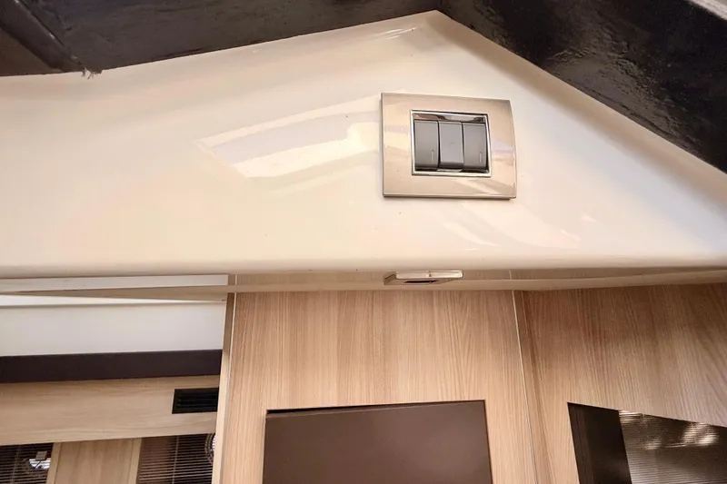 Slide: The Image of 2016 Cranchi M44 HT yacht interior with porthole, control panel, and wooden finish. - 90