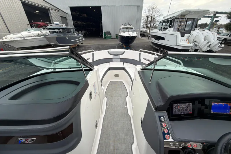 Slide: The Image of 2018 Chaparral 267 SSX boat interior with dashboard and seating, docked near other boats. - 25