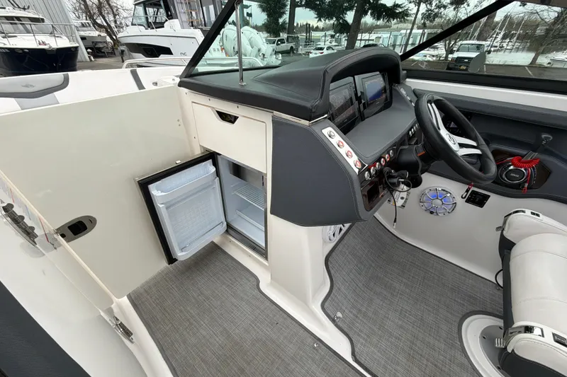 Slide: The Image of 2018 Chaparral 267 SSX boat interior with open mini fridge and modern dashboard. - 27