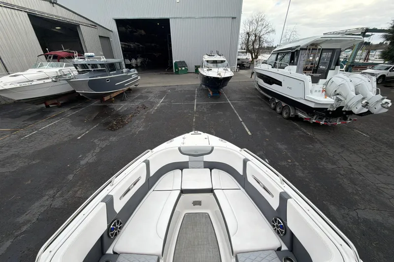 Slide: The Image of 2018 Chaparral 267 SSX boat in marina with other vessels and storage building. - 28