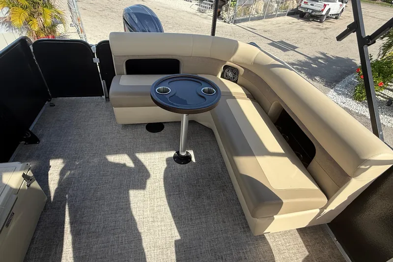 Slide: The Image of 2024 Premier Sunspree boat interior with beige seating and round table, outdoor setting. - 19