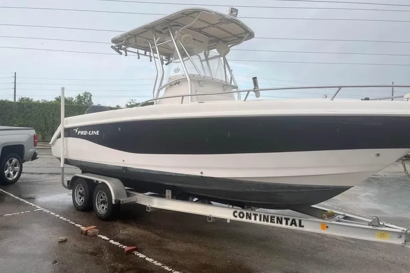 Slide: The Image of 2005 Pro-Line 24 Sport boat on trailer, parked outdoors under clear blue sky. - 2