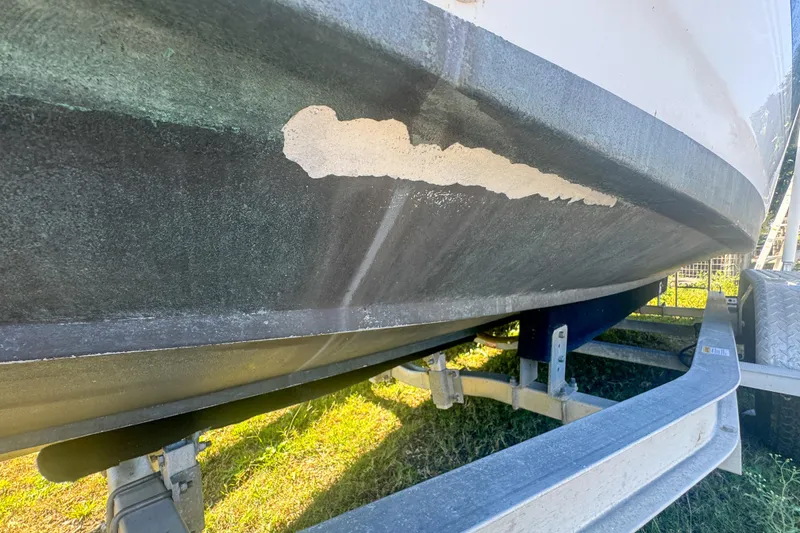 Slide: The Image of 2005 Pro-Line 24 Sport boat hull with visible paint damage on trailer. - 45