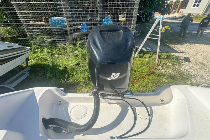 Slide: The Image of 2005 Pro-Line 24 Sport boat engine, outdoor setting, ladder and people in background. - 59