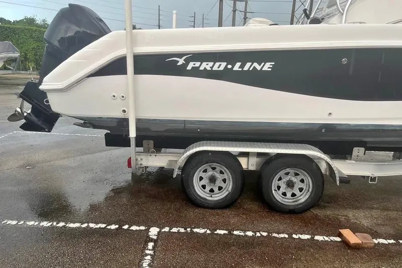 Slide: The Image of 2005 Pro-Line 24 Sport boat on trailer with outboard motor, parked outdoors. - 6