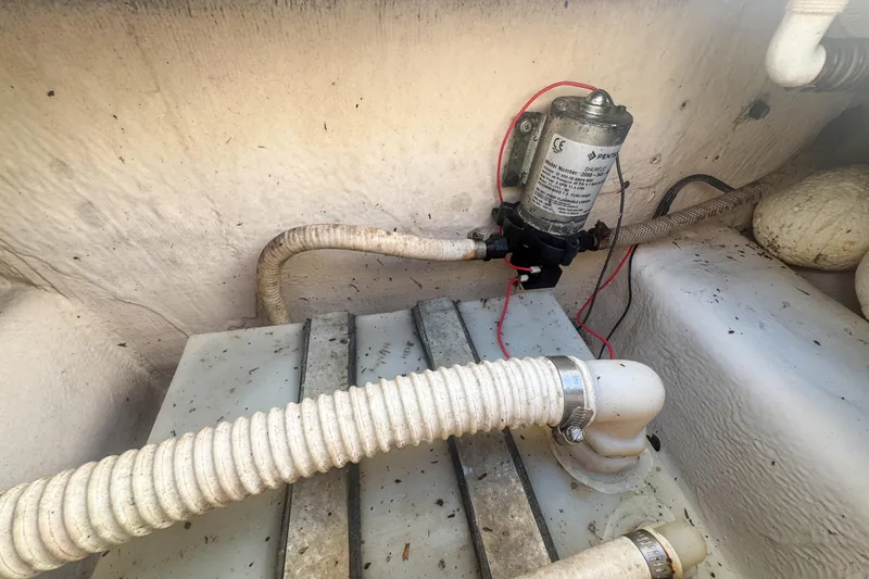 Slide: The Image of 2005 Pro-Line 24 Sport boat bilge area with pump and hoses. - 62