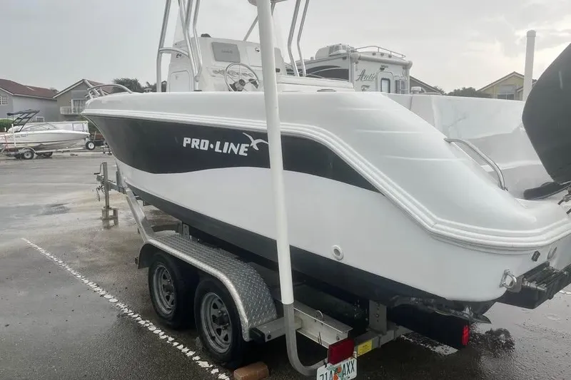 Slide: The Image of 2005 Pro-Line 24 Sport boat on trailer with outboard motor, parked on grass. - 7