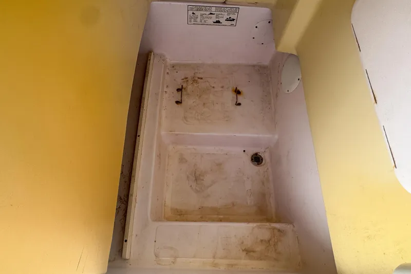 Slide: The Image of 2005 Pro-Line 24 Sport boat interior, showing a storage compartment with visible wear. - 94