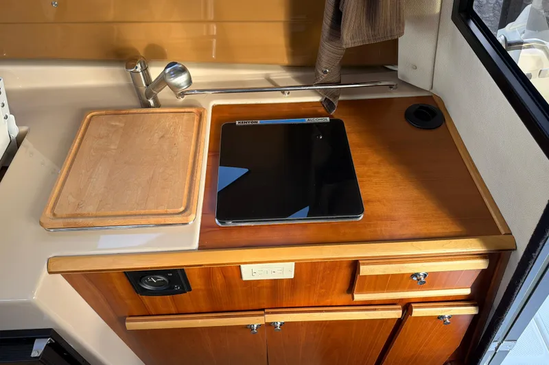 Slide: The Image of Compact kitchen area in a 2016 Cutwater C-242 Coupe boat with stove and cutting board. - 31