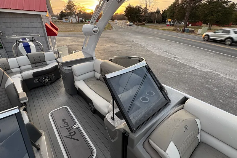 Slide: The Image of 2023 Avalon Excalibur 2585 Windshield Elite boat interior with seating and windshield, at sunset. - 12
