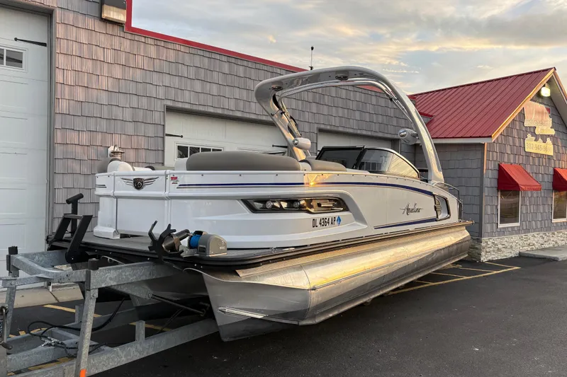 Slide: The Image of 2023 Avalon Excalibur 2585 Windshield Elite Tri Toon on trailer, parked outside building. - 3