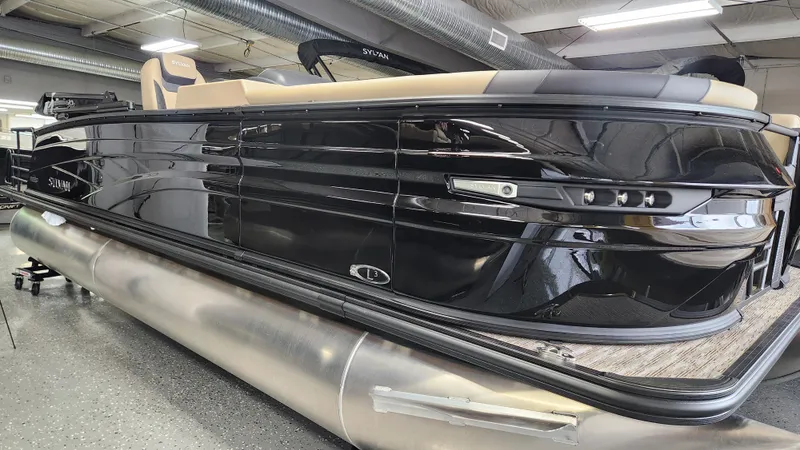 Slide: The Image of A sleek, modern pontoon boat with a black hull and beige interior in a showroom. - 42