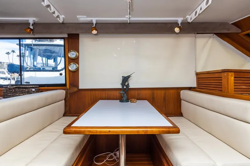Slide: The Image of 1987 Californian 48 Convertible yacht interior dining area with white cushioned seating and wooden table. - 35