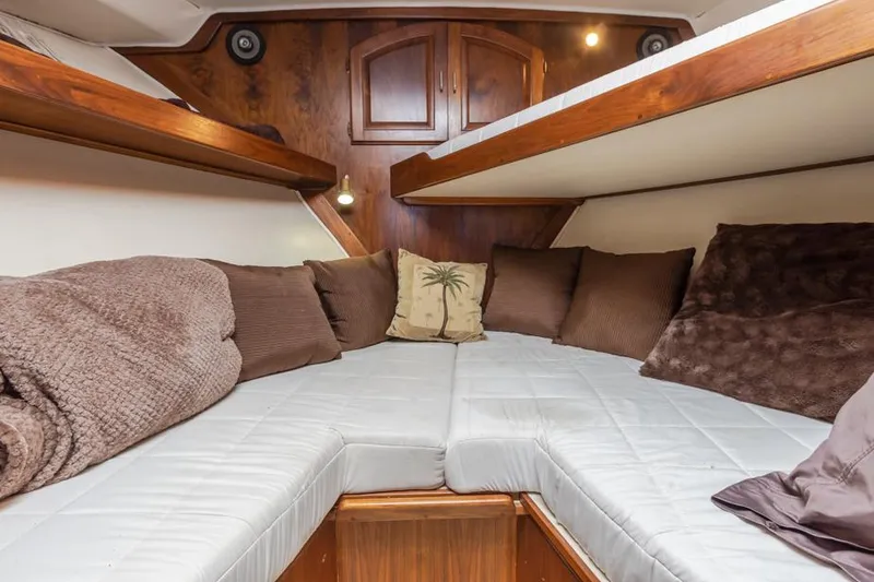 Slide: The Image of Cozy cabin interior of a 1987 Californian 48 Convertible yacht with plush bedding and wooden accents. - 47