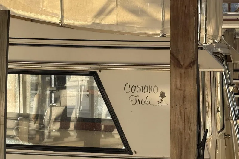 Slide: The Image of 2002 Camano Troller boat docked, featuring rear cabin entrance and ladder under a wooden canopy. - 10