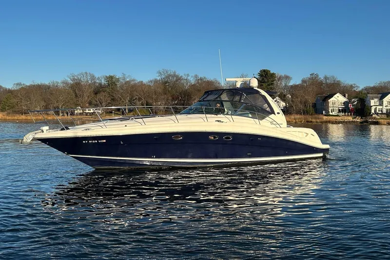 The Image of 2003 Sea Ray 420 Sundancer yacht on calm water, with houses in the background. - 0