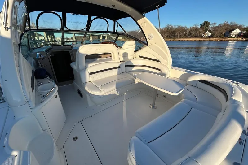 Slide: The Image of 2003 Sea Ray 420 Sundancer boat interior with white seating and table on calm water. - 3