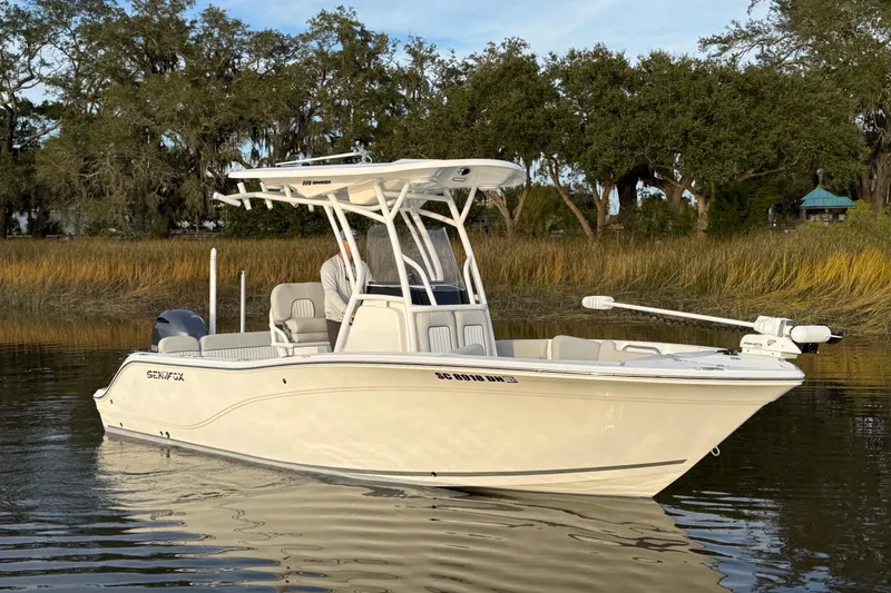 Slide: The Image of 2021 Sea Fox 228 Commander boat on calm water, surrounded by trees. - 2