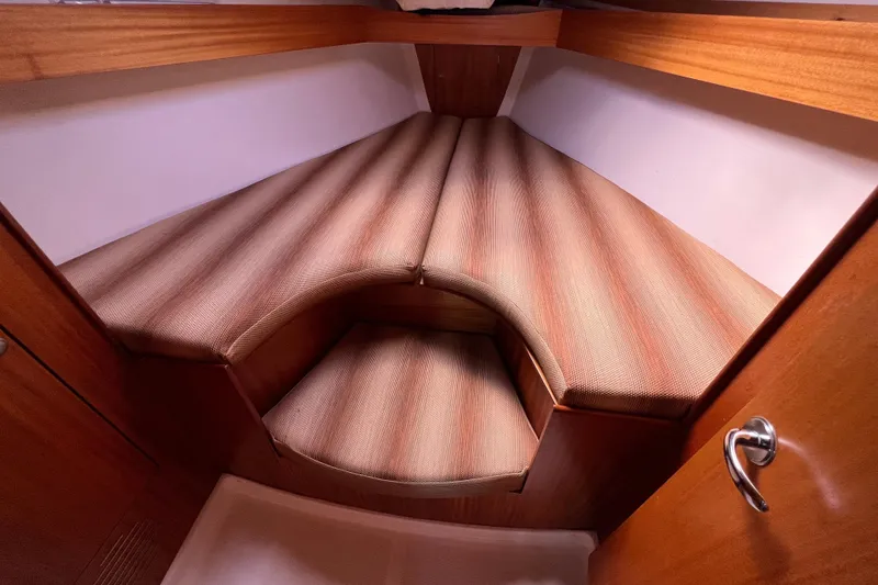 Slide: The Image of 2007 Delphia 33 Sloop interior cabin with striped cushions and wooden finish. - 85