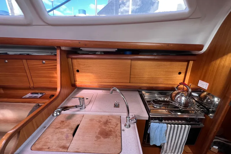 Slide: The Image of Interior of a 2007 Delphia 33 Sloop, featuring a compact kitchen with wooden cabinetry. - 92