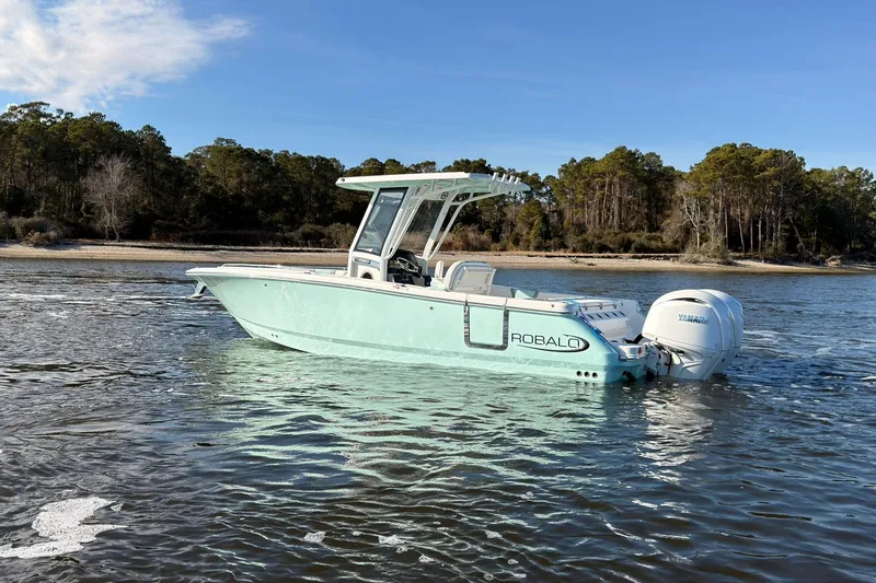 Slide: The Image of 2025 Robalo R250 Center Console boat on water, scenic forest background. - 34