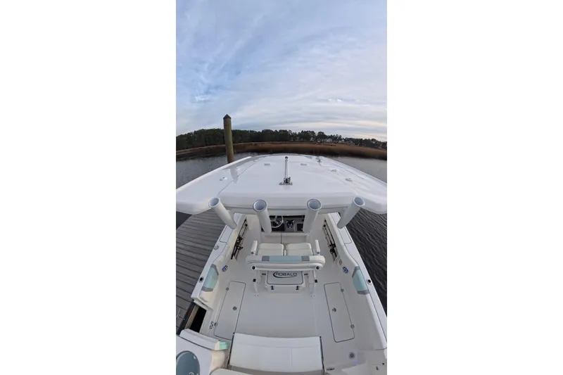 Slide: The Image of 2025 Robalo R250 Center Console boat navigating a calm marina with docked ships. - 9