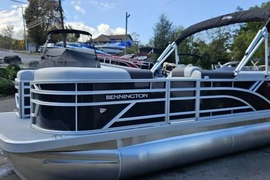 Slide: The Image of 2026 Bennington 20 SL pontoon boat with sleek design, docked outdoors. - 2