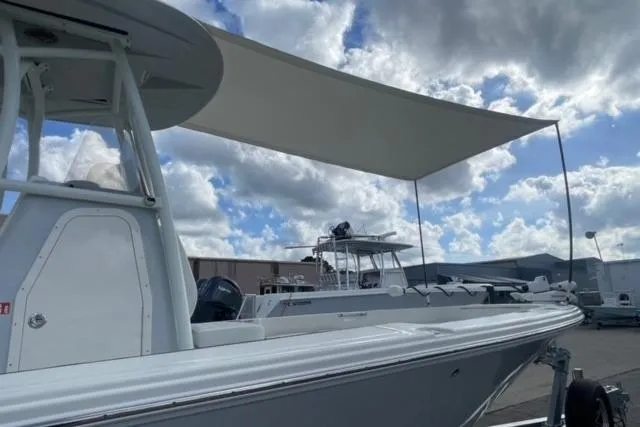 Slide: The Image of 2026 Pathfinder 2600 TRS boat with canopy, parked under a cloudy sky. - 7