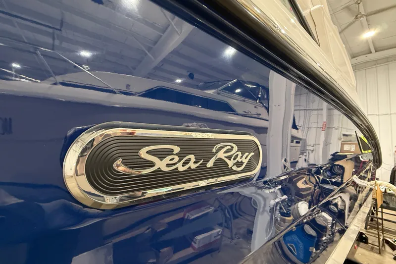 Slide: The Image of 2026 Sea Ray SDX 270 boat with sleek blue exterior and chrome logo in a showroom. - 25