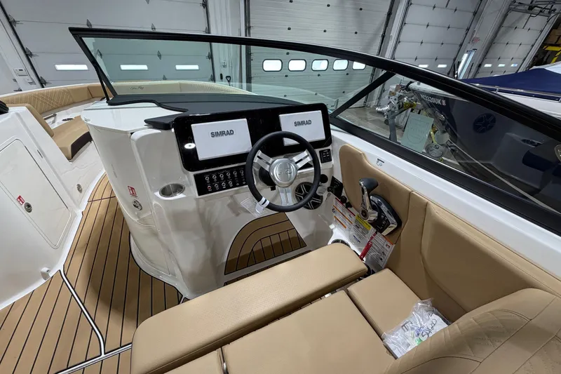 Slide: The Image of 2026 Sea Ray SDX 250 boat interior with modern dashboard and steering wheel in a showroom. - 10