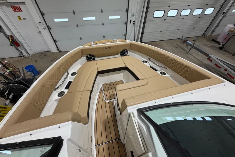 Slide: The Image of 2026 Sea Ray SDX 250 boat interior with tan seating and wood flooring in a garage. - 12