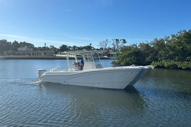 The Image of 2025 World Cat 295 CC boat cruising on a calm river under a clear blue sky. - 1