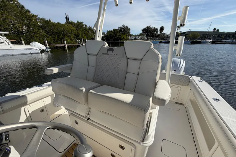 Slide: The Image of 2025 World Cat 295 CC boat interior with comfortable seating and steering wheel, docked by the water. - 10