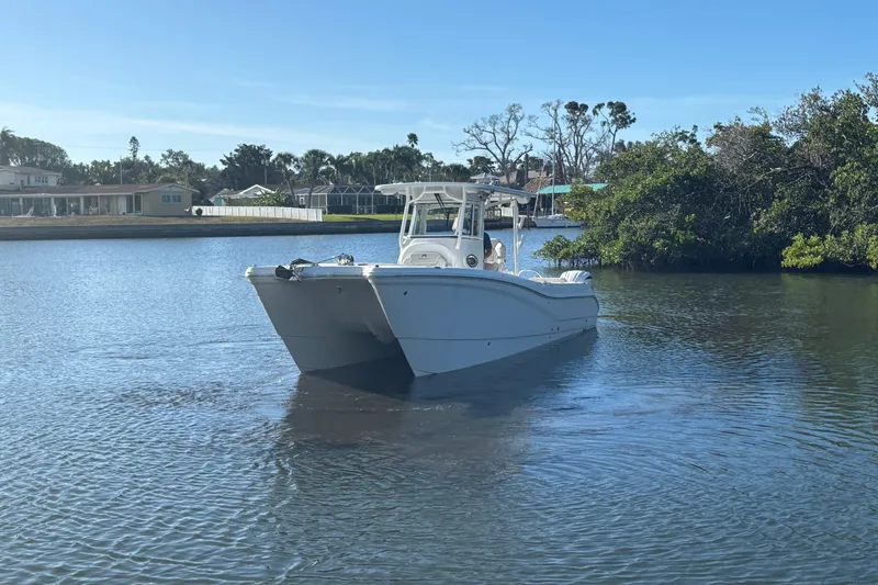 Slide: The Image of 2025 World Cat 295 CC boat cruising on a calm river near lush greenery. - 4