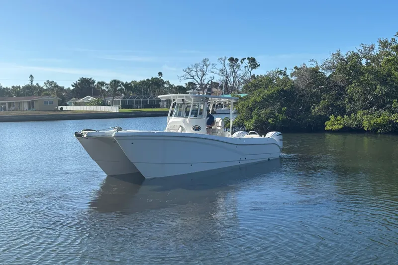Slide: The Image of 2025 World Cat 295 CC boat on calm water near lush greenery. - 5