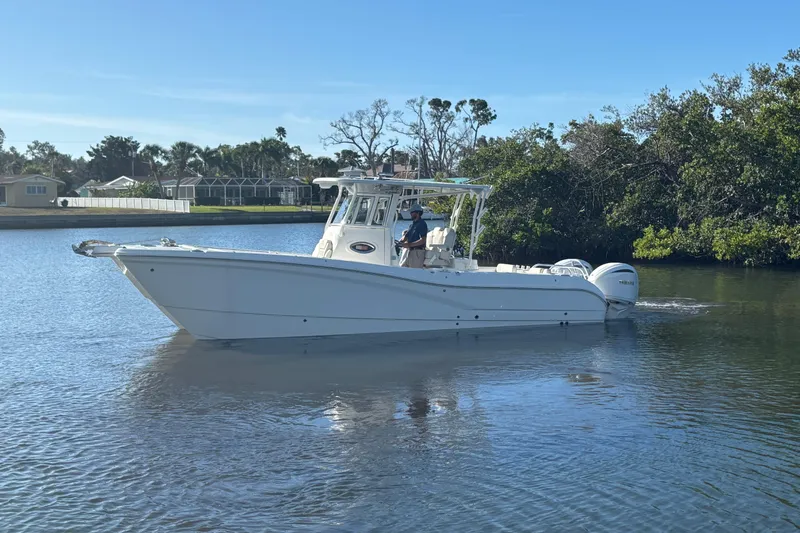 Slide: The Image of 2025 World Cat 295 CC boat cruising on a calm river, surrounded by lush greenery. - 6