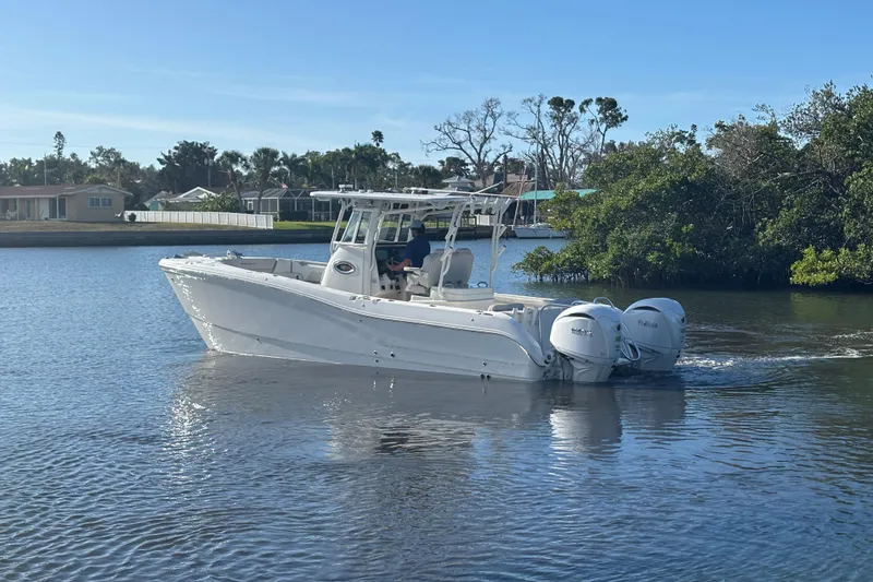 Slide: The Image of 2025 World Cat 295 CC boat cruising on a calm waterway near lush greenery. - 7