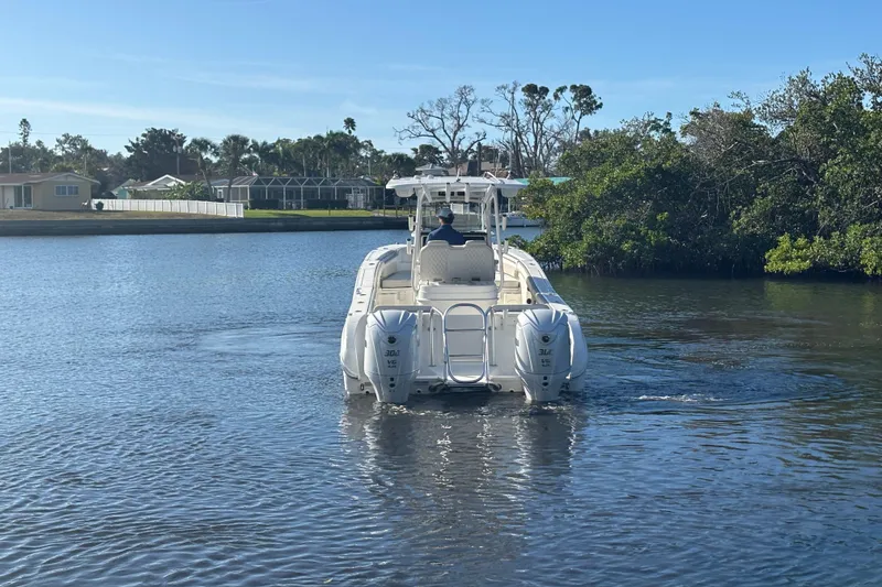 Slide: The Image of 2025 World Cat 295 CC boat cruising on a calm waterway, surrounded by greenery. - 8