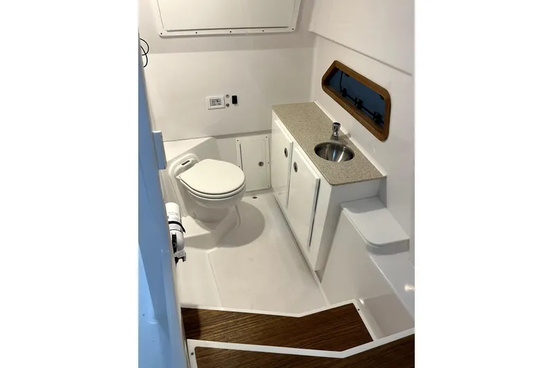 Slide: The Image of 2023 Bertram 28 CC boat interior bathroom with toilet, sink, and wooden flooring. - 12